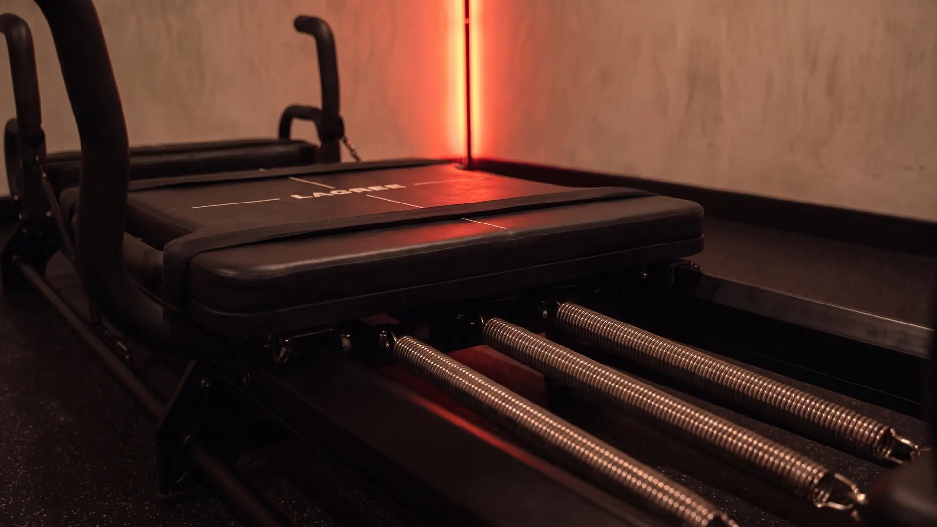 Le chariot d’une machine Micro Pro, ressorts tendus, sous la lumière rouge de la barre LED du studio