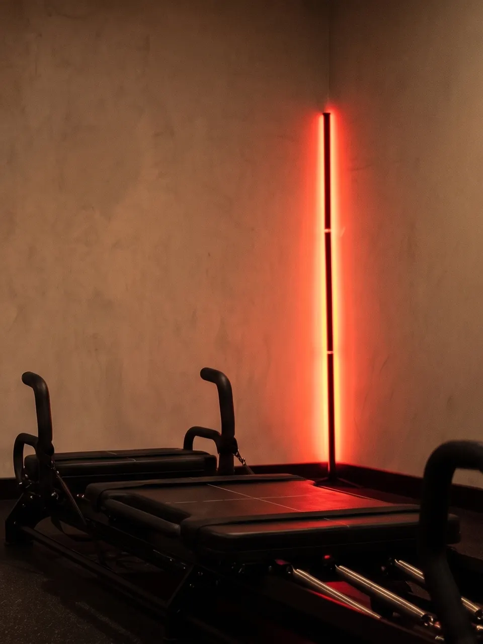 La barre LED rouge du studio sur le mur greige, dans la pénombre