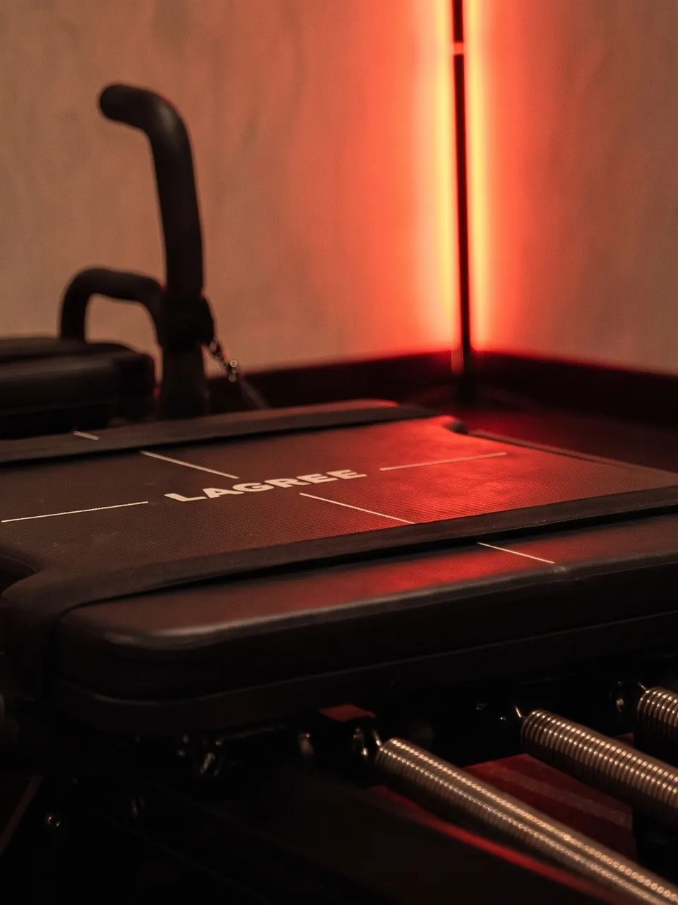 Le chariot d’une Micro Pro glisse sur ses rails, ressorts apparents, dans la lumière rouge